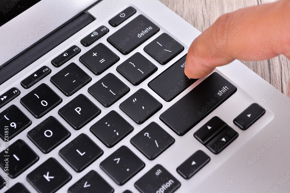 Hand touching laptop computer keyboard - Focus on the keyboard Hand touching laptop computer keyboard - Focus on the keyboard