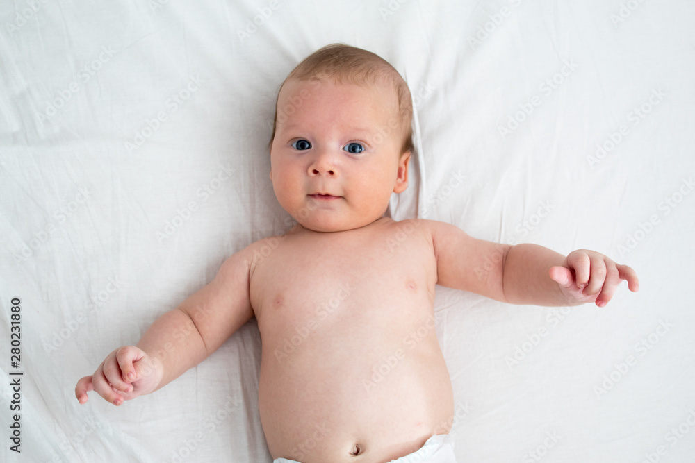 The baby a surprised expression. Newborn lying on a white background .Top view The baby a surprised expression. Newborn lying on a white background .Top view