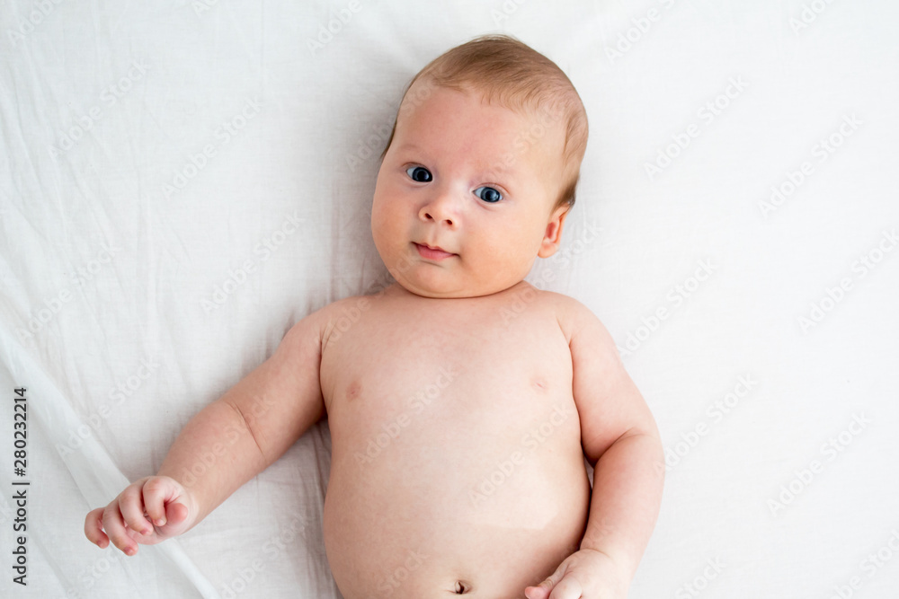 The baby smiles. Newborn lying on a white background .Top view The baby smiles. Newborn lying on a white background .Top view