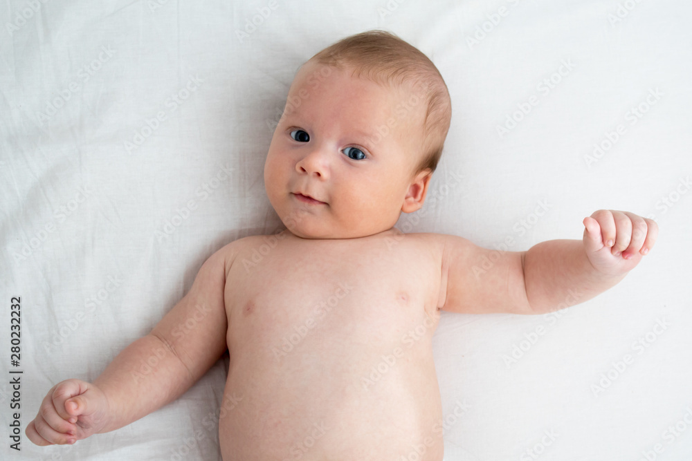 The baby smiles. Newborn lying on a white background .Top view The baby smiles. Newborn lying on a white background .Top view
