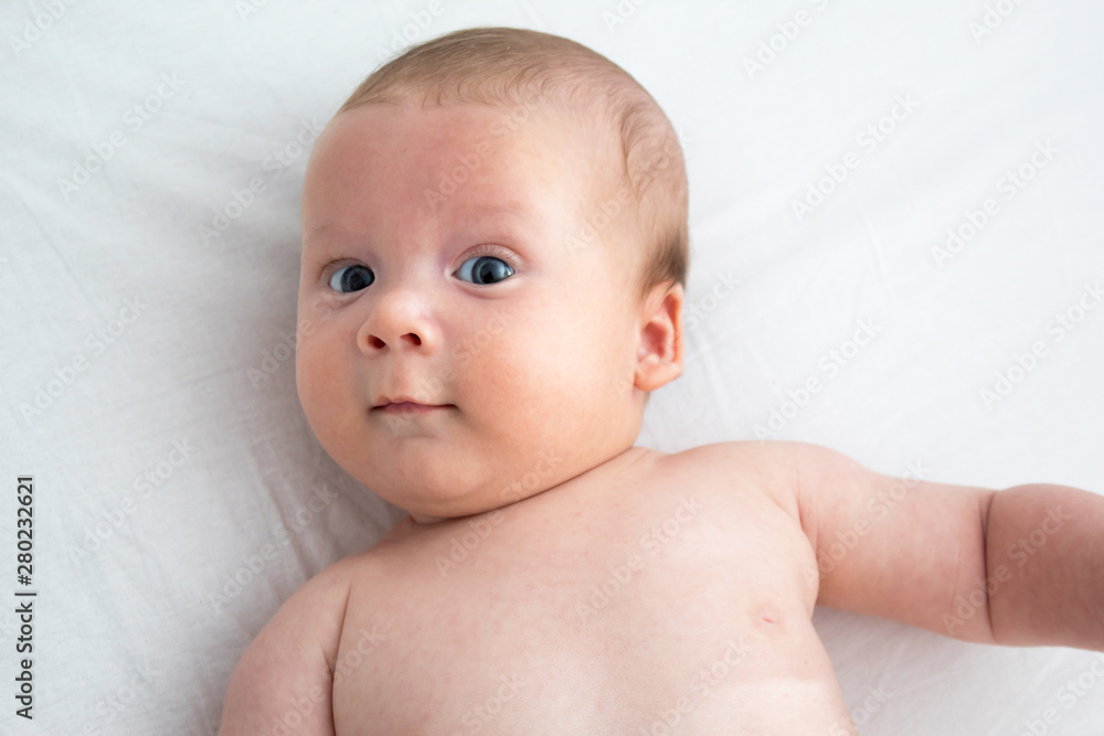 The baby a surprised expression. Newborn lying on a white background .Top view The baby a surprised expression. Newborn lying on a white background .Top view