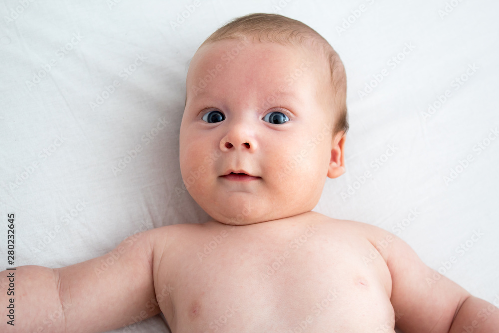 The baby a surprised expression. Newborn lying on a white background .Top view