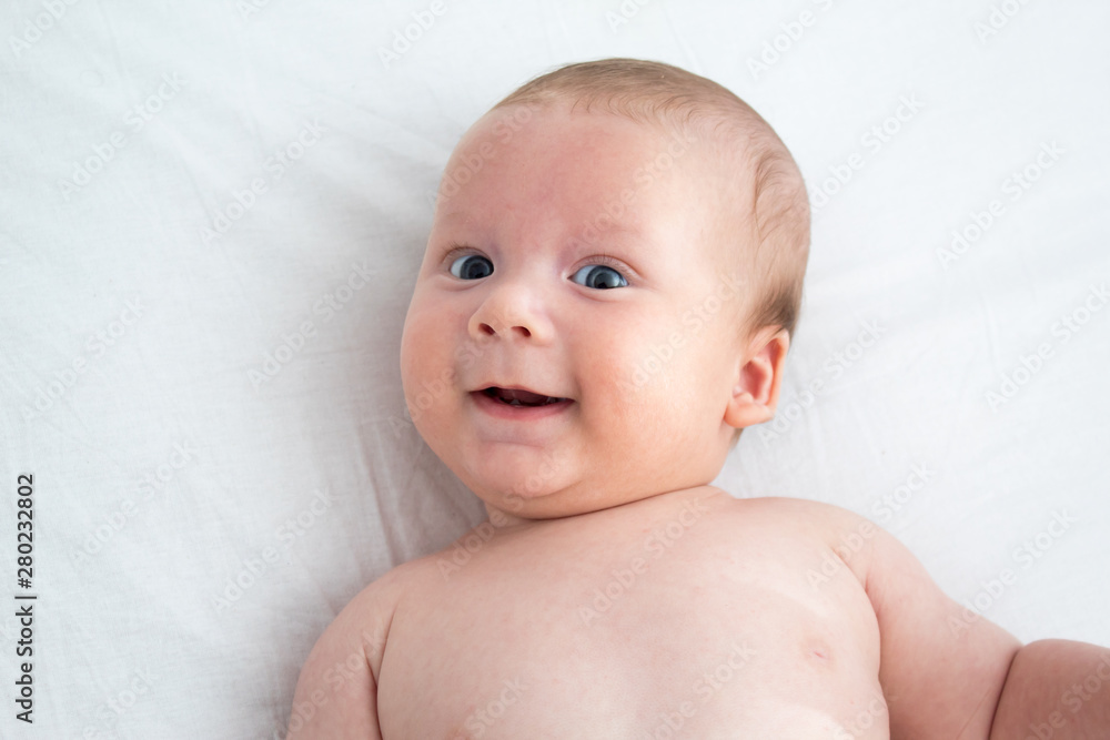 The baby smiles. Newborn lying on a white background .Top view The baby smiles. Newborn lying on a white background .Top view