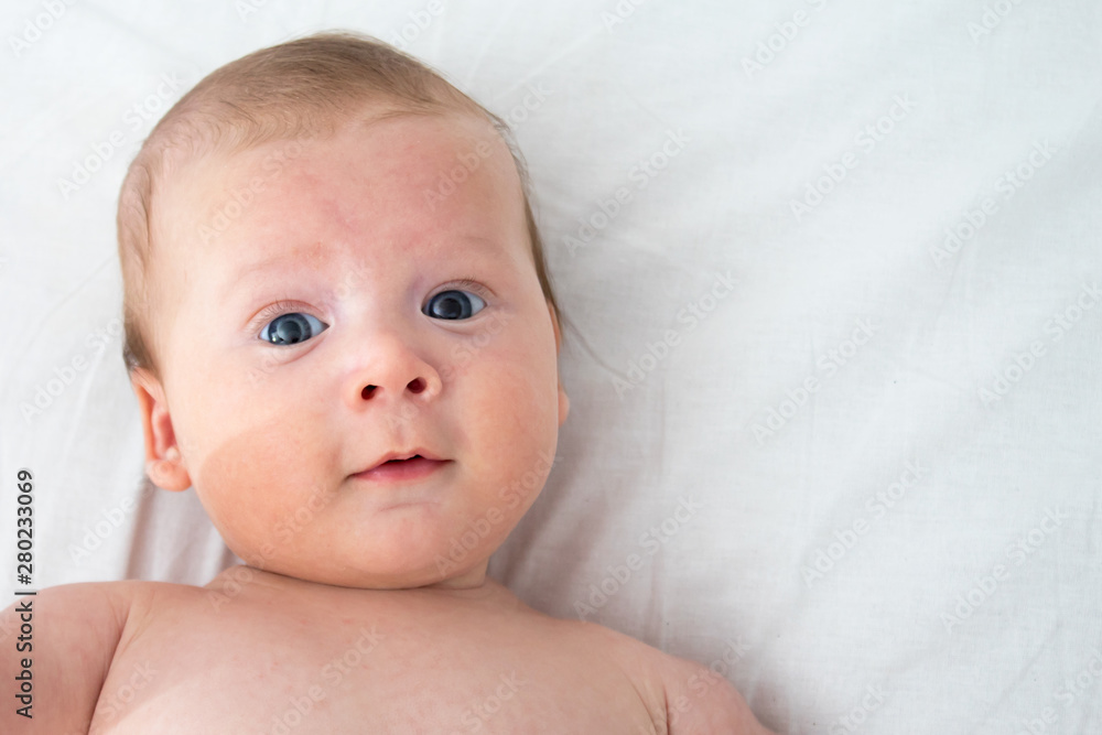 The baby a surprised expression. Newborn lying on a white background .Top view The baby a surprised expression. Newborn lying on a white background .Top view