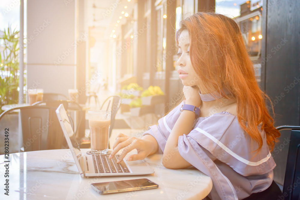 Portrait of successful young woman with laptop in street cafe with sunlight