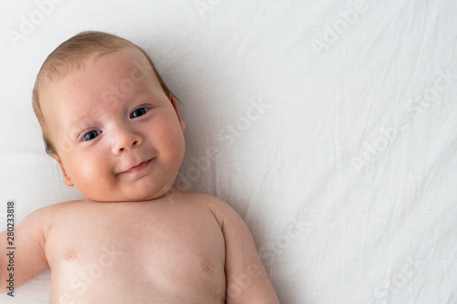 The baby smiles. Newborn lying on a white background .Top view