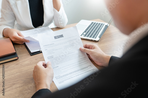 Serious man has a business meeting reading a resume about hiring decision during a job interview in company, attractive and professionally dressed, employment recruitment concept.