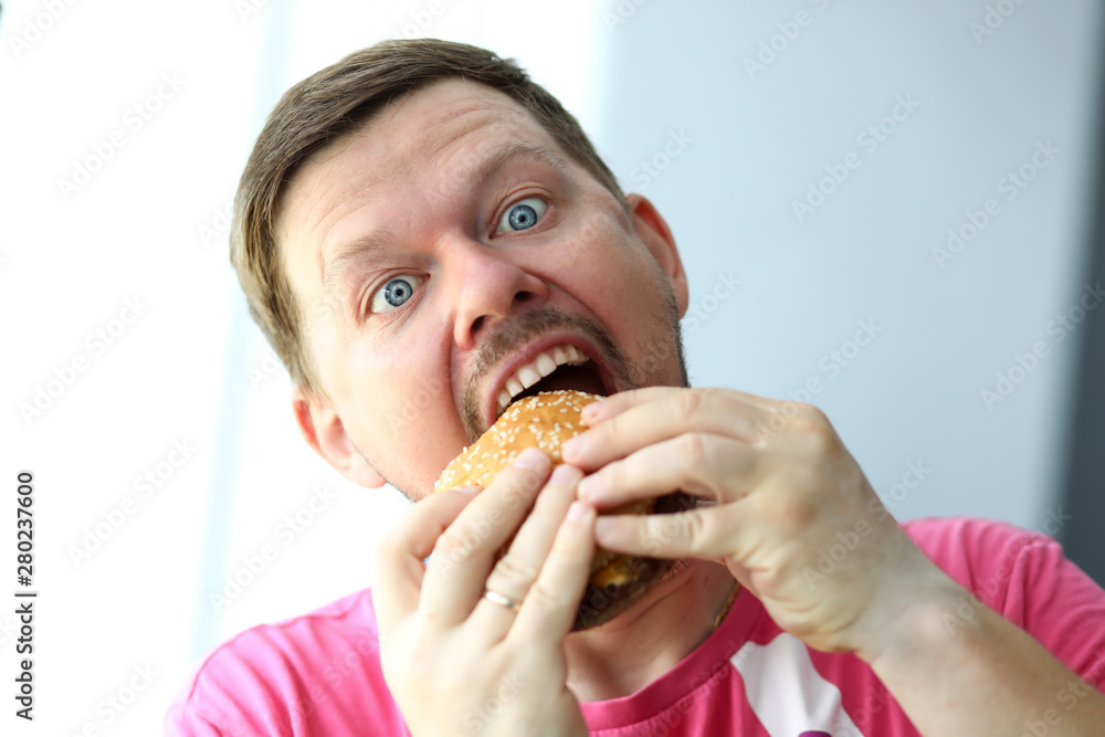 Funny bearded man with idiot facial expression eating burger Funny bearded man with idiot facial expression eating burger