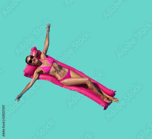 Relaxed woman pink on inflatable matrass over blue photo