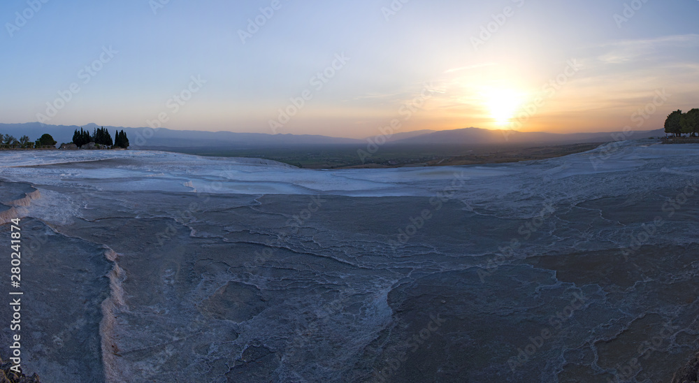 Obraz premium Turkey, sunset on the travertine terraces at Pamukkale (Cotton Castle), natural site of sedimentary rock deposited by water from the hot springs, famous for a carbonate mineral left by flowing water