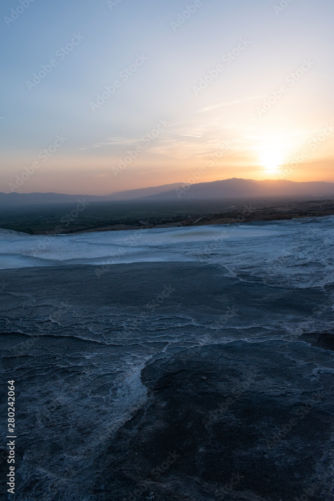Turkey, sunset on the travertine terraces at Pamukkale (Cotton Castle), natural site of sedimentary rock deposited by water from the hot springs, famous for a carbonate mineral left by flowing water