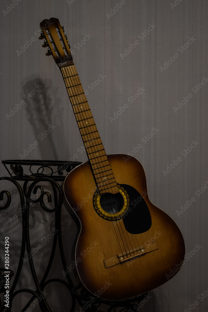 Obraz premium classic acoustic guitar propped in front of a white wall as background