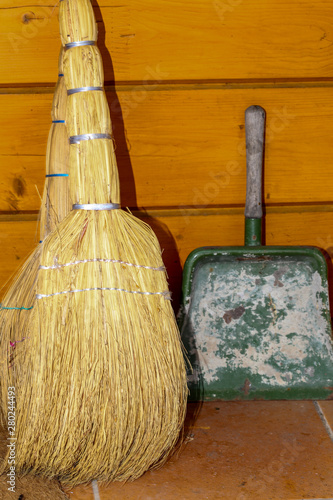 Wallpaper Mural Two natural straw brooms and an old metal scoop on the background of the wooden wall of the house. Torontodigital.ca