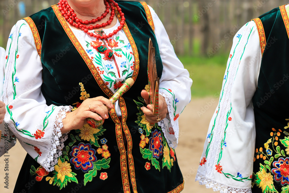 An elderly woman in a Ukrainian embroidered shirt plays folk instruments at the ethnic festival in Petrykivka, Dnipropetrovsk region, summer, Ukraine