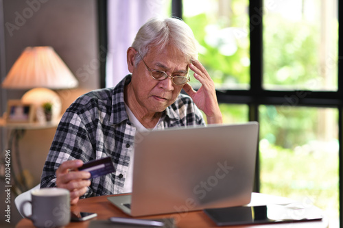 Fotografie Asian senior man looking confuse when using credit card for online shopping