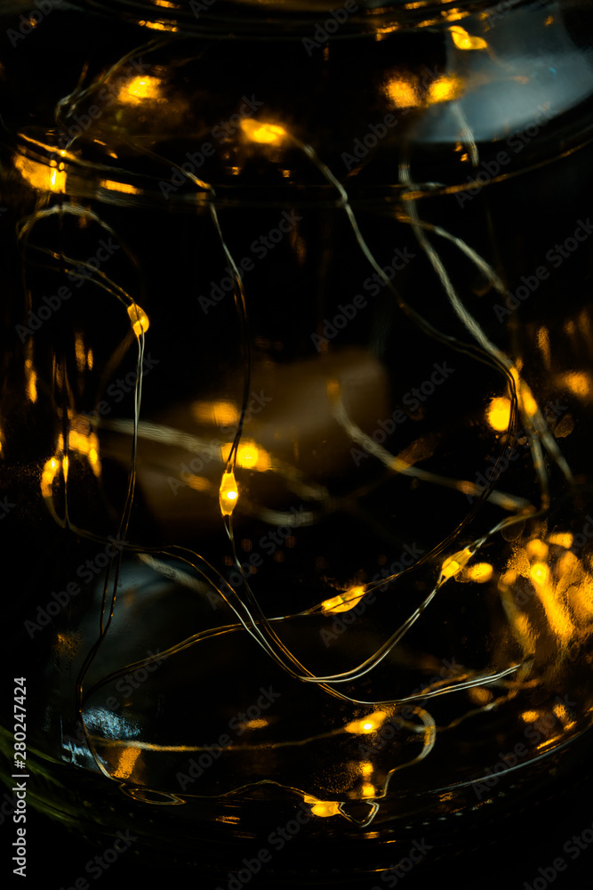Decorative lights in glass jar at the dark room with mirror effect on dark background. Festive decorations .Warm white led lights. Decorative lights in glass jar at the dark room with mirror effect on dark background. Festive decorations .Warm white led lights.