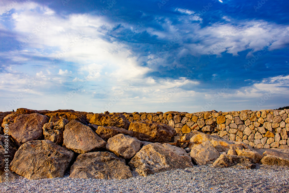 A low wall of stone with a blue little cloudy sky.