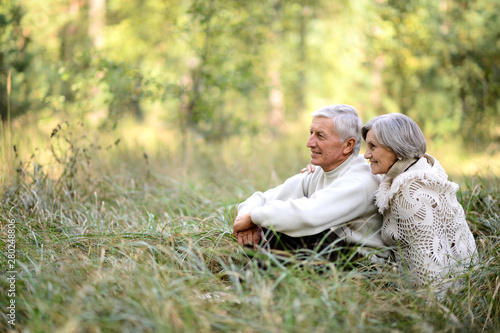 Portrait of elderly couple sitting in autumn nature