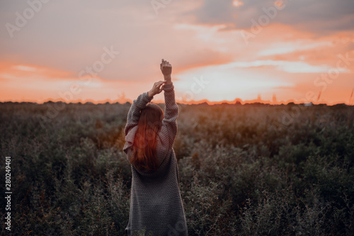 Woman enjoying nature in meadow. Outstretched arms fresh morning air summer Field at sunrise.
