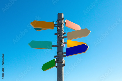 Guidepost with bright colored arrows against blue sky