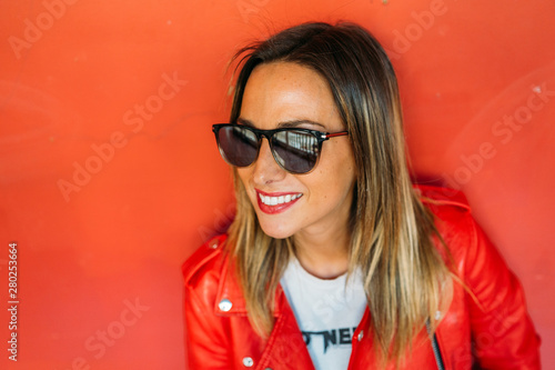 Image of happy young cute woman standing isolated over red background. Looking at the left. Copy space image.