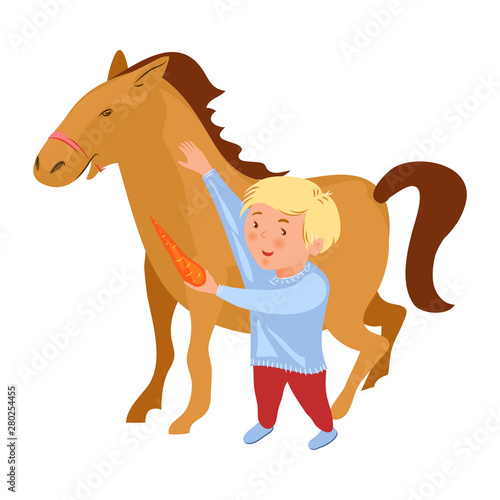 Cute blonde hair boy give fresh red carrot to horse