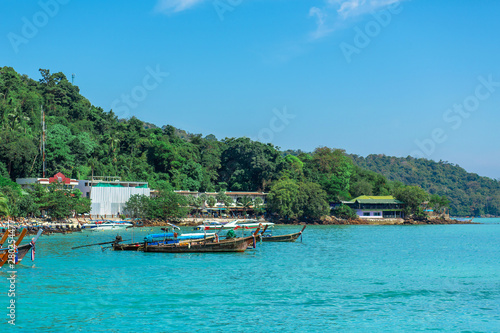 Traditional Thai fishing boats wrapped with colored ribbons. Against the backdrop of a tropical island