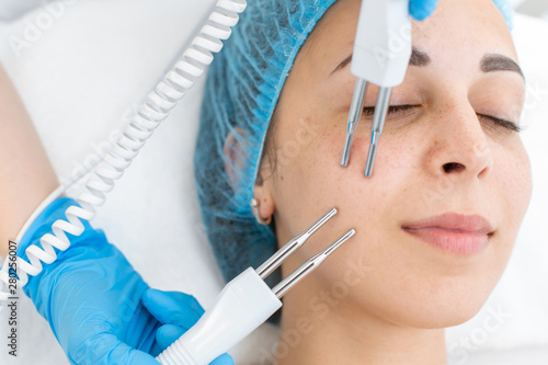 Beautician procedure of microcurrent therapy of the patient s face. A young girl is undergoing a course of spa treatments in the office of a beautician. Moisturizing  cleaning and facial skin care