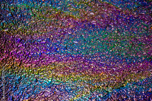 A leaked Car Oil Petrol in The Rain on a Tarmac Road Metallic Rainbow