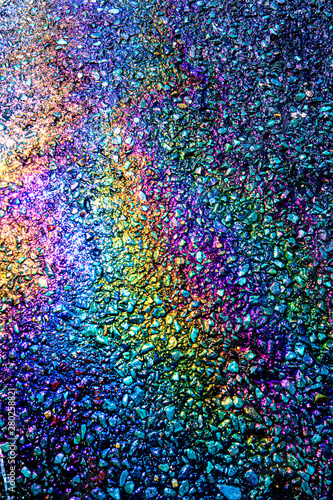 A leaked Car Oil Petrol in The Rain on a Tarmac Road Metallic Rainbow