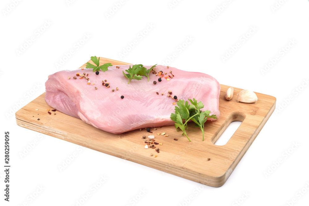 Raw turkey fillet with parsley and spices on a wooden cutting board over white background. Raw turkey fillet with parsley and spices on a wooden cutting board over white background.