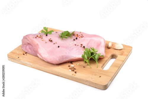 Raw turkey fillet with parsley and  spices on a wooden cutting board over white background.