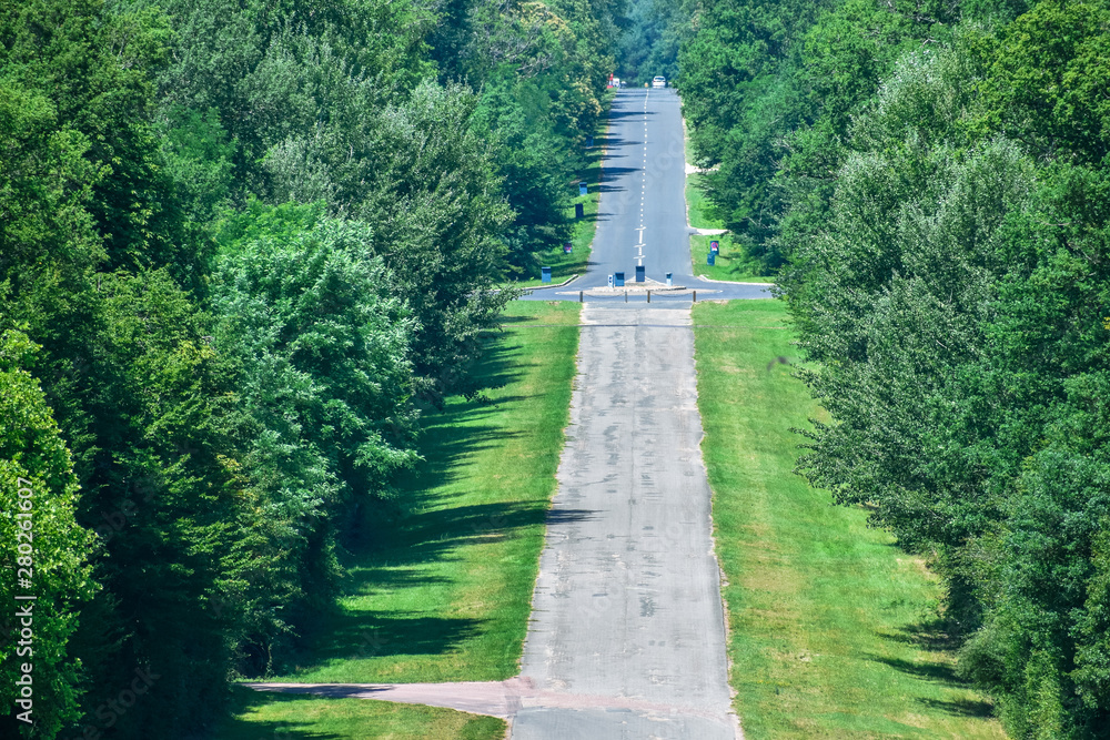 Long asphalt straight road through the forest. Road with ups and downs. Sunny and cloudy day. Long asphalt straight road through the forest. Road with ups and downs. Sunny and cloudy day.