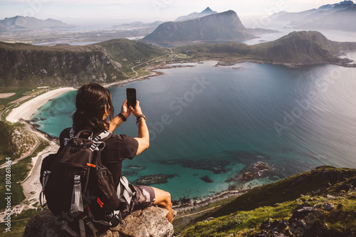 Man with a cellphone sitting in a rock taking photos of the view