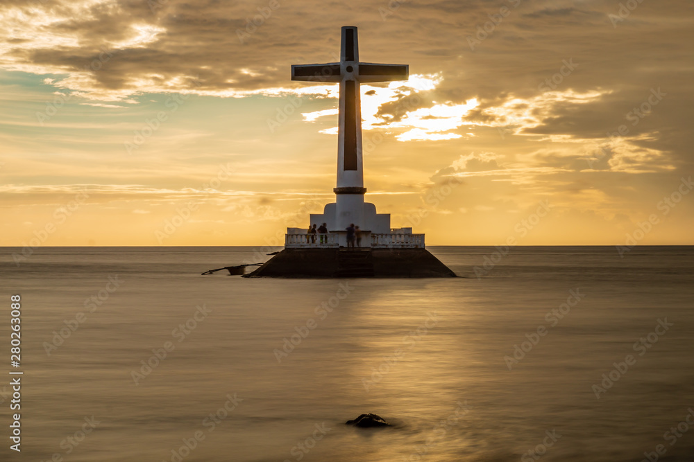 Sunset behind a large cross marking an old, sunken cemetery under the tropical ocean (Camiguin, Philippines)