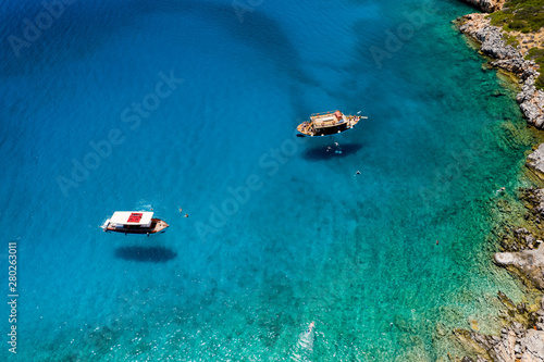 Aerial drone view of traditional Greek wooden boats floating on the crystal clear waters of the Aegean Sea (Crete) © whitcomberd