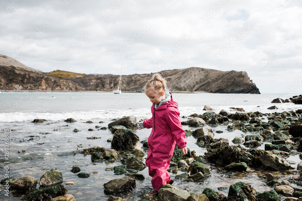 blonde girl walking on rocks at the beach at lulworth cove, England blonde girl walking on rocks at the beach at lulworth cove, England
