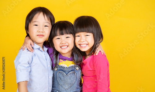 Obraz na plátně Portrait group of young happy little asian girls boy on yellow background with copy space
