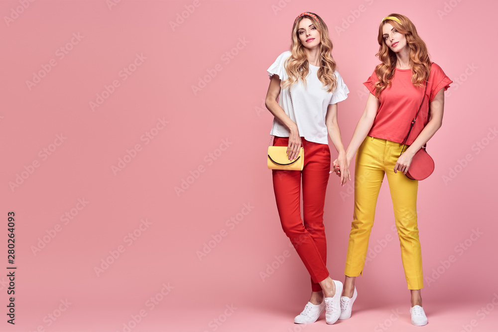 Fashionable embracing woman sisters smiling on pink background. Two Shapely Girl Having Fun dance, Trendy yellow coral summer outfit, fashion hairstyle, makeup. Gorgeous female model, funny concept Fashionable embracing woman sisters smiling on pink background. Two Shapely Girl Having Fun dance, Trendy yellow coral summer outfit, fashion hairstyle, makeup. Gorgeous female model, funny concept