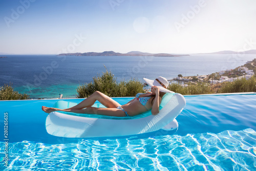 Attraktive Frau im Bikini sonnt sich auf einer Luftmatratze im Pool und genießt den Sommer
