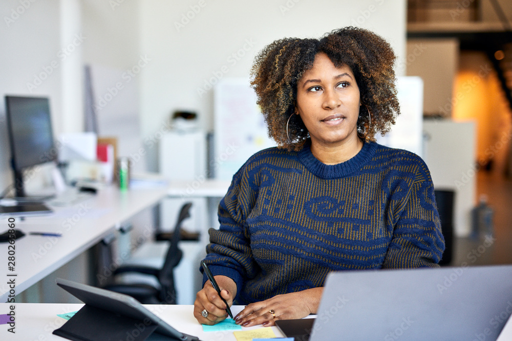 Thoughtful businesswoman with adhesive notes on desk standing in office Thoughtful businesswoman with adhesive notes on desk standing in office
