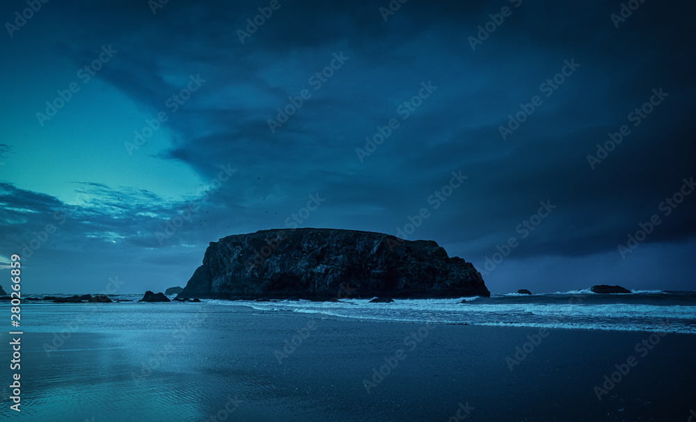 Sea stack called Table Rock in Bandon Oregon, storm clouds in evening sky