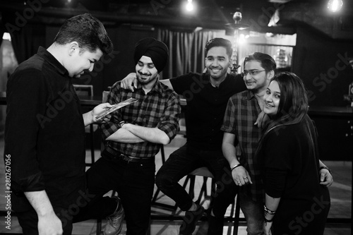 Group of indian friends sitting at lounge bar, having rest and look at menu.