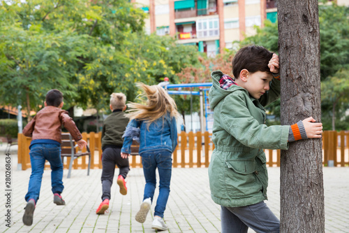 Φωτογραφία Boy playing hide and seek with friends