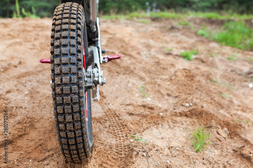 Skid-resistant tread on motorcycle tire, motocross bike in sandy track, rear view photo
