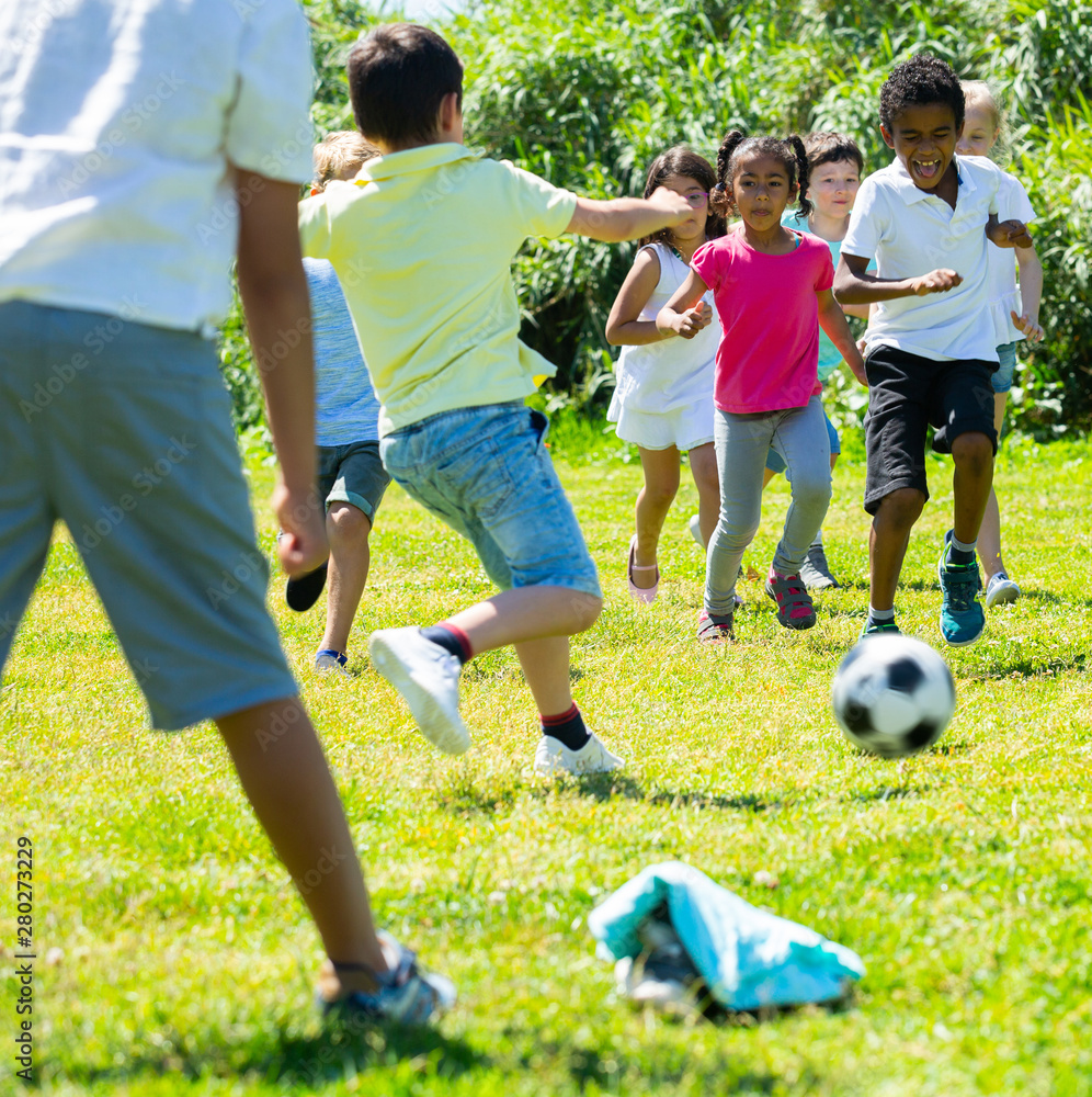 Obraz premium Happy kids are jogning and playing football in the park