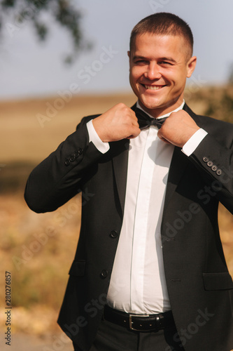 Handsome groomm dressed a tie bow. Wedding day. Man outside. Young man smile photo