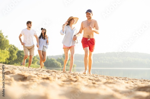 Group of friends having fun running down the beach