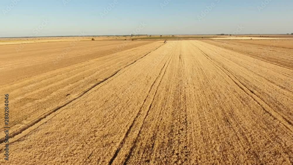 Aerial shot of a fast-flying drone rushing to a standing combine in wheat field Aerial shot of a fast-flying drone rushing to a standing combine in wheat field