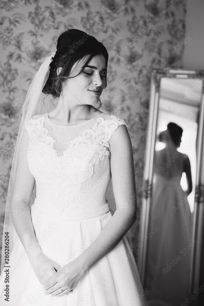 Naklejka premium Beautiful bride stand by the window. Morning with sunlights. Black and white photo